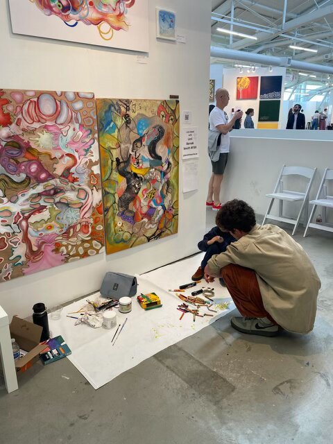 A person adding to collaborative artwork at an art fair