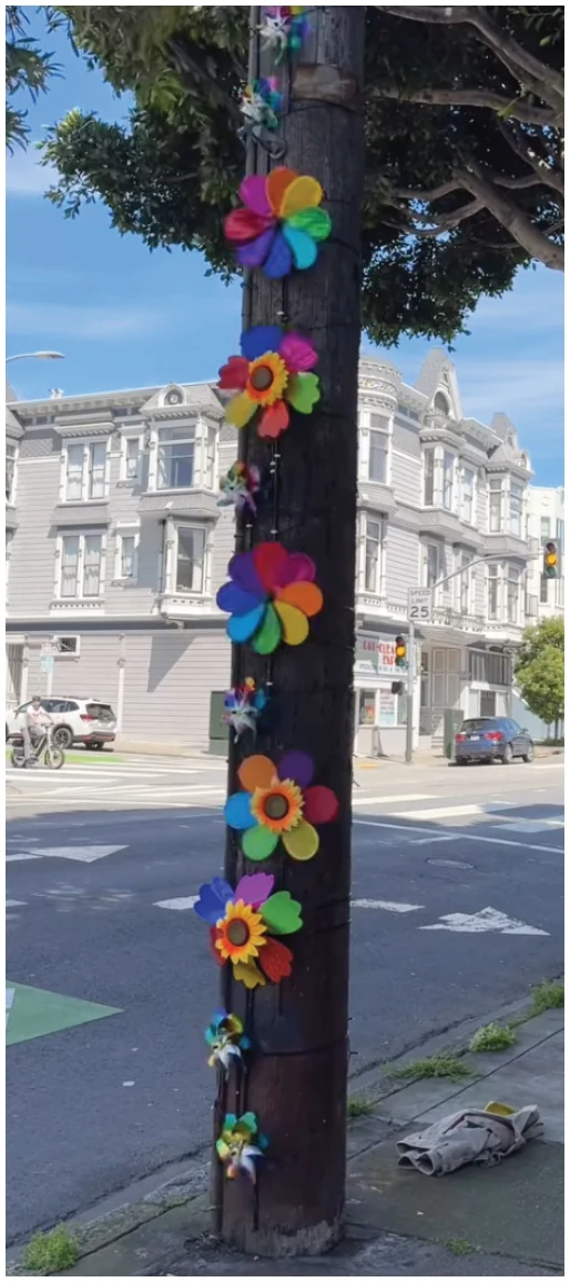 Photograph of colorful pinwheels wrapped around an Oak Street tree.