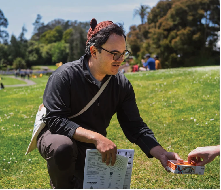 Photograph of Sage Kitamorn distributing Cozy Cubs puzzles.